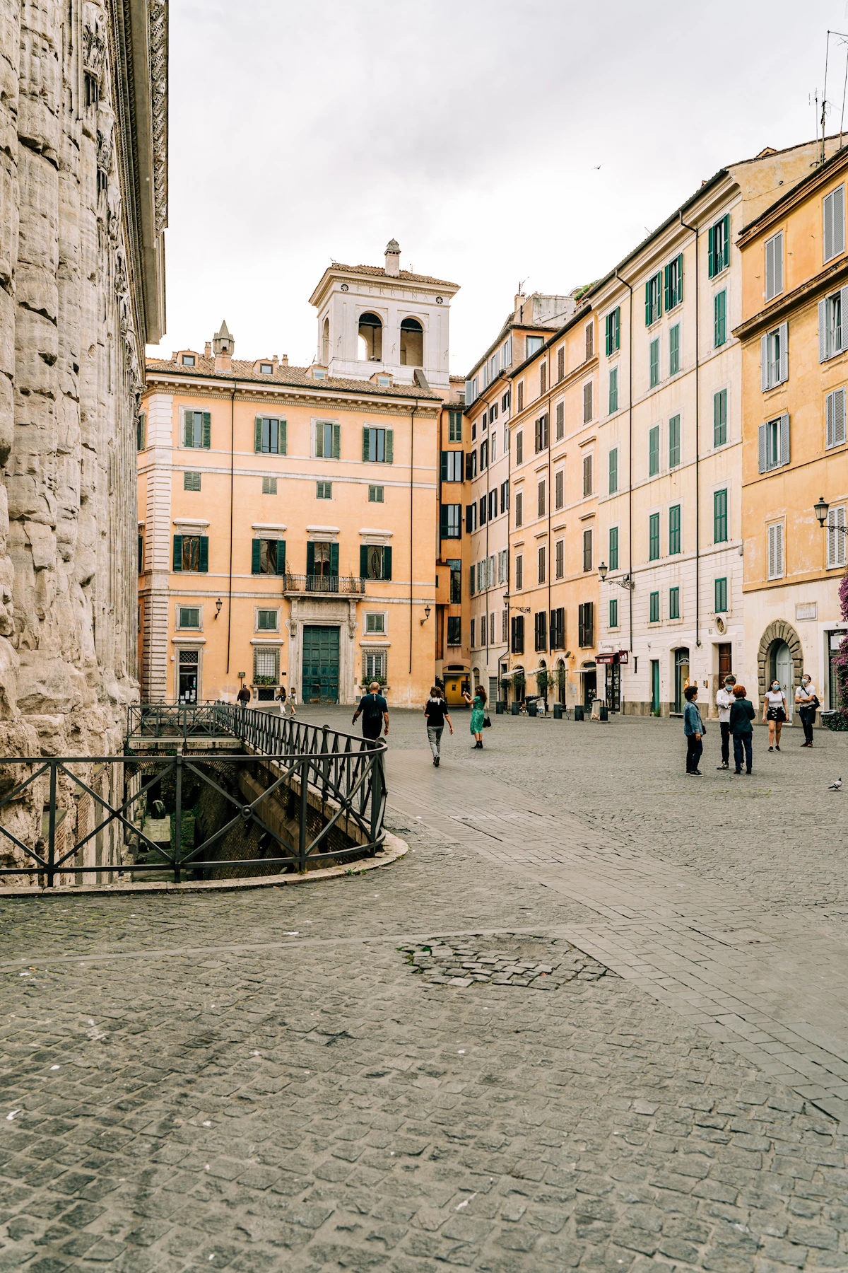 Piazza di Pietra a Roma: il fianco in travertino del Tempio di Adriano e i palazzi color albicocca con le persiane verdi