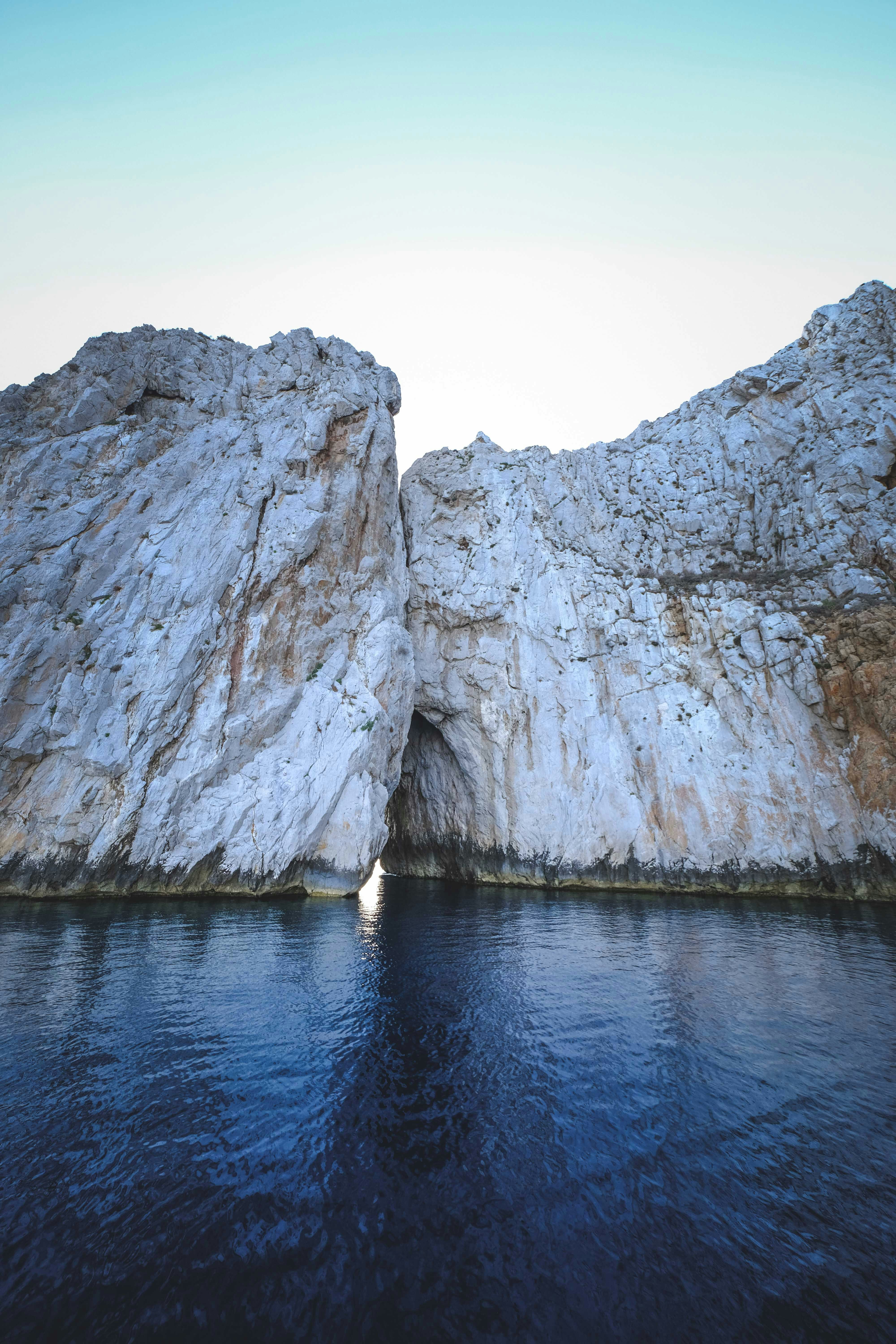 gray rock formation on body of water during daytime