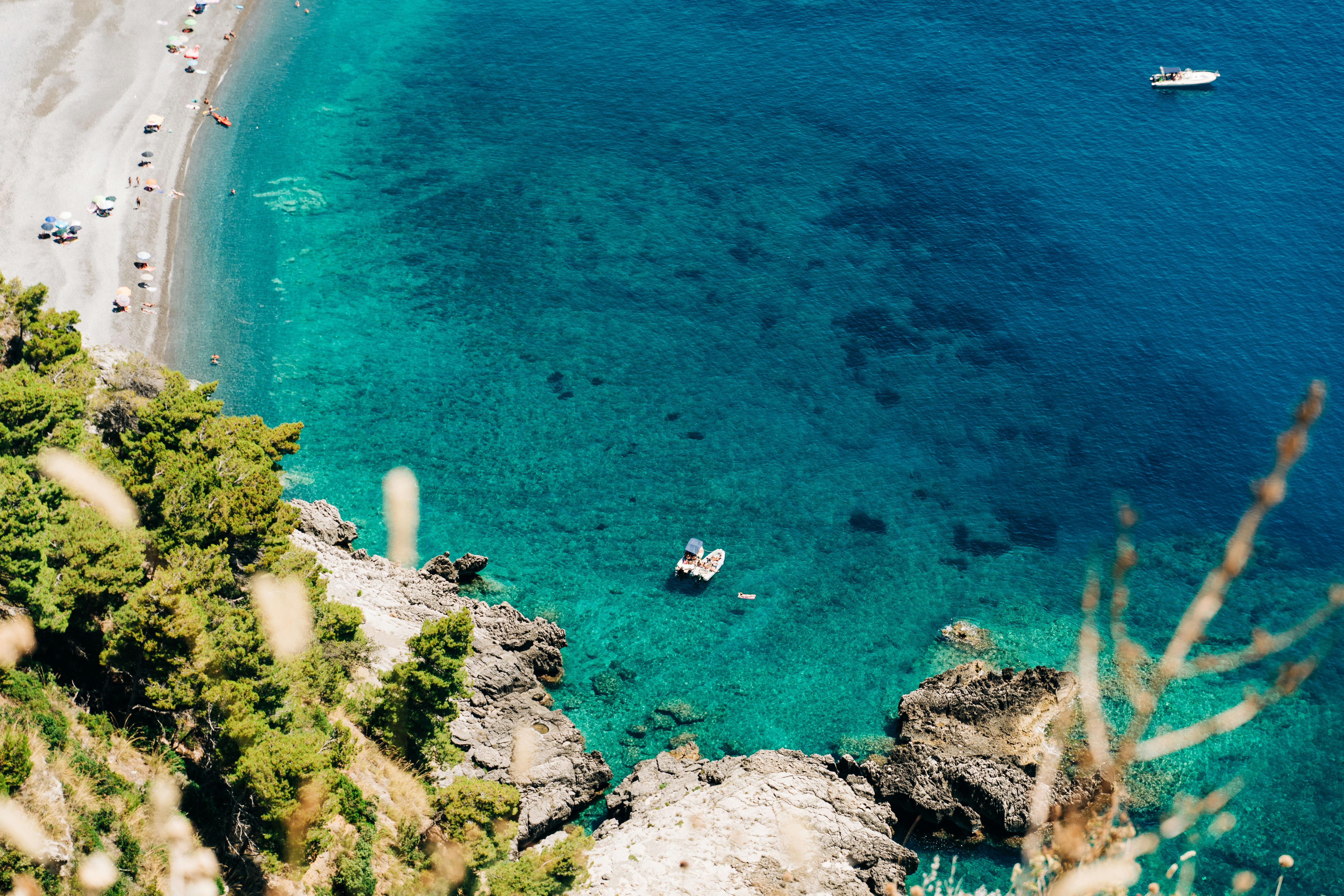 aerial view of people on beach during daytime, People sunbathing on boats in the crystal clear sea off the coast of Basilicata, Italy
