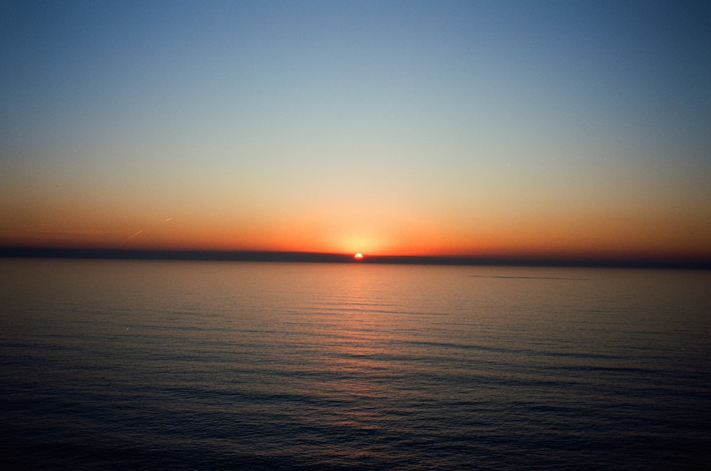 the sun is setting over the ocean on a clear day