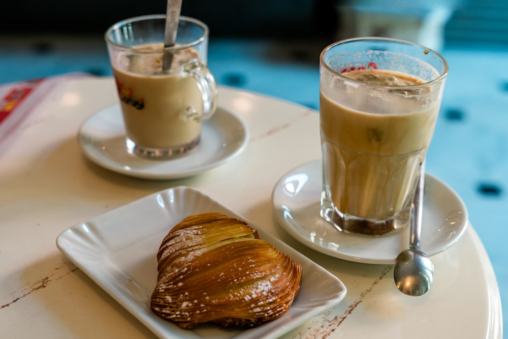 Tasse en verre transparent avec liquide brun sur soucoupe en céramique blanche