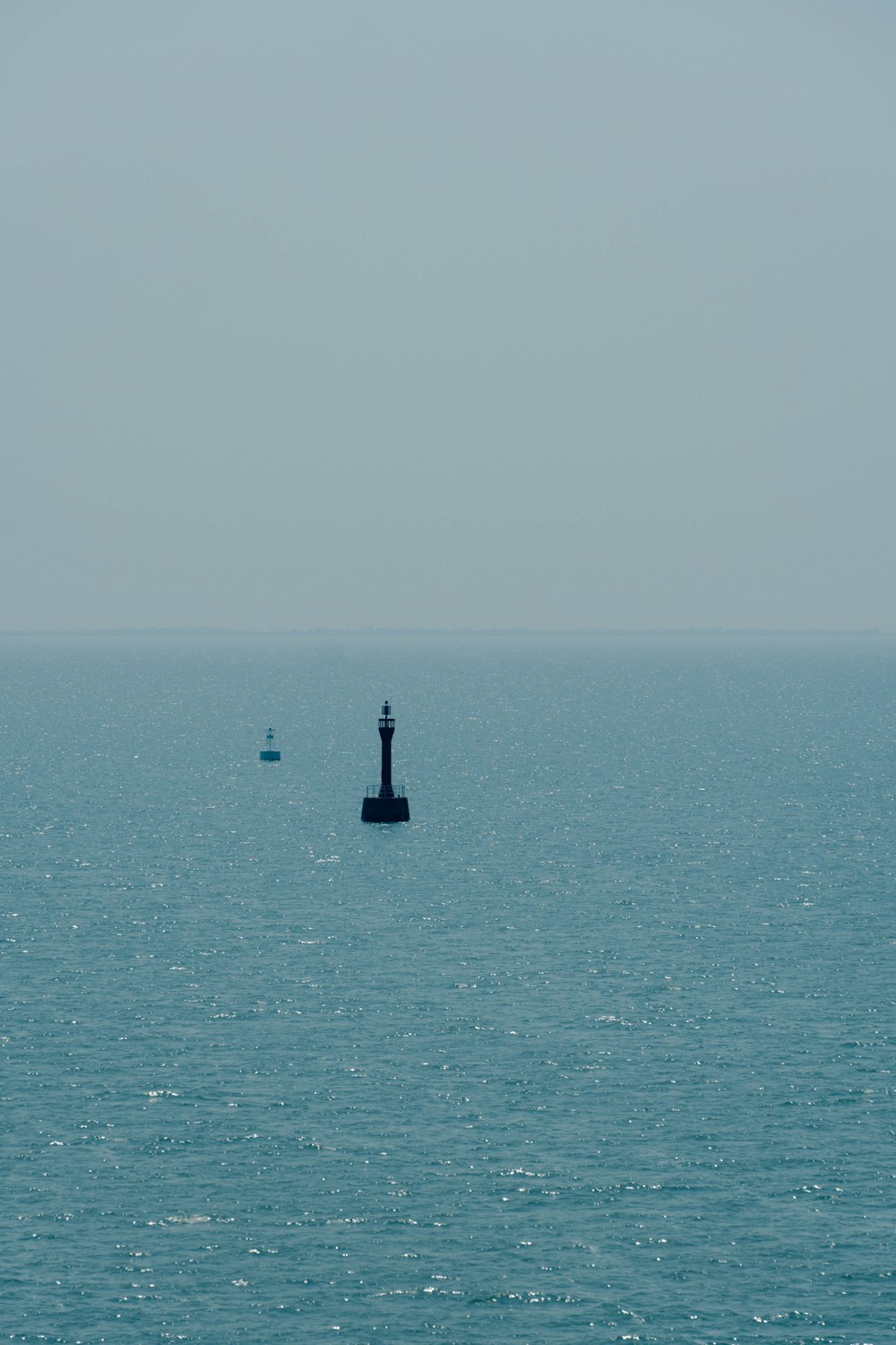 silhouette of person standing on rock in the middle of the sea