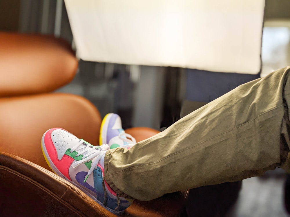 person in gray denim jeans and white and pink nike sneakers