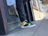 A happy customer wearing bright stridevibe sneakers, smiling while standing on a city sidewalk.
