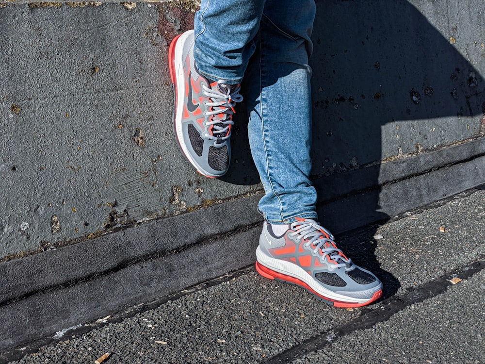 person in blue denim jeans wearing red and white nike sneakers