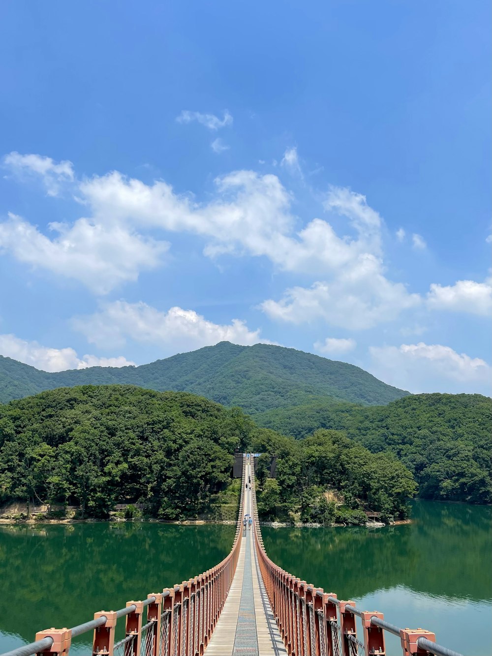 green mountain beside body of water under blue sky during daytime