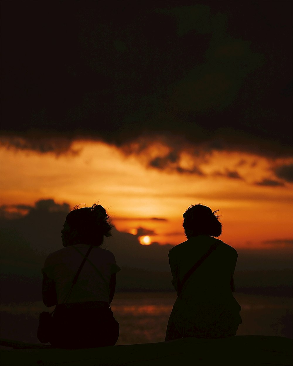 Silueta del hombre y de la mujer de pie durante la puesta del sol