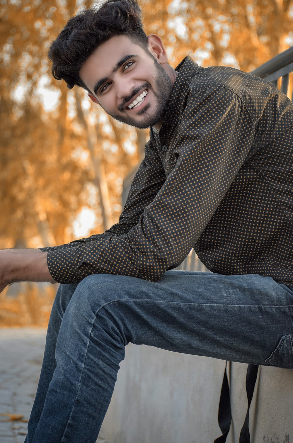 man in brown and black checkered dress shirt and blue denim jeans sitting on brown wooden