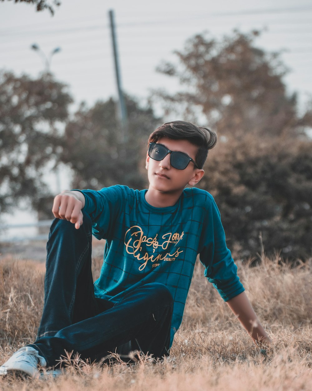 man in blue and white crew neck long sleeve shirt and black pants sitting on brown