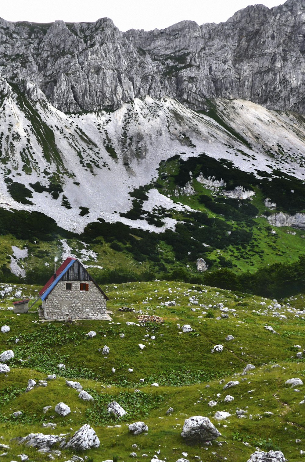 Casa azul y blanca en un campo de hierba verde cerca de la montaña durante el día