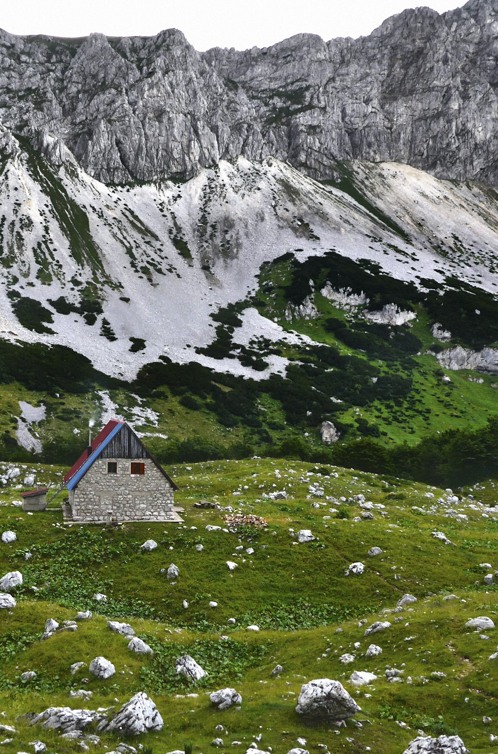 Maison bleue et blanche sur un champ d’herbe verte près de la montagne pendant la journée