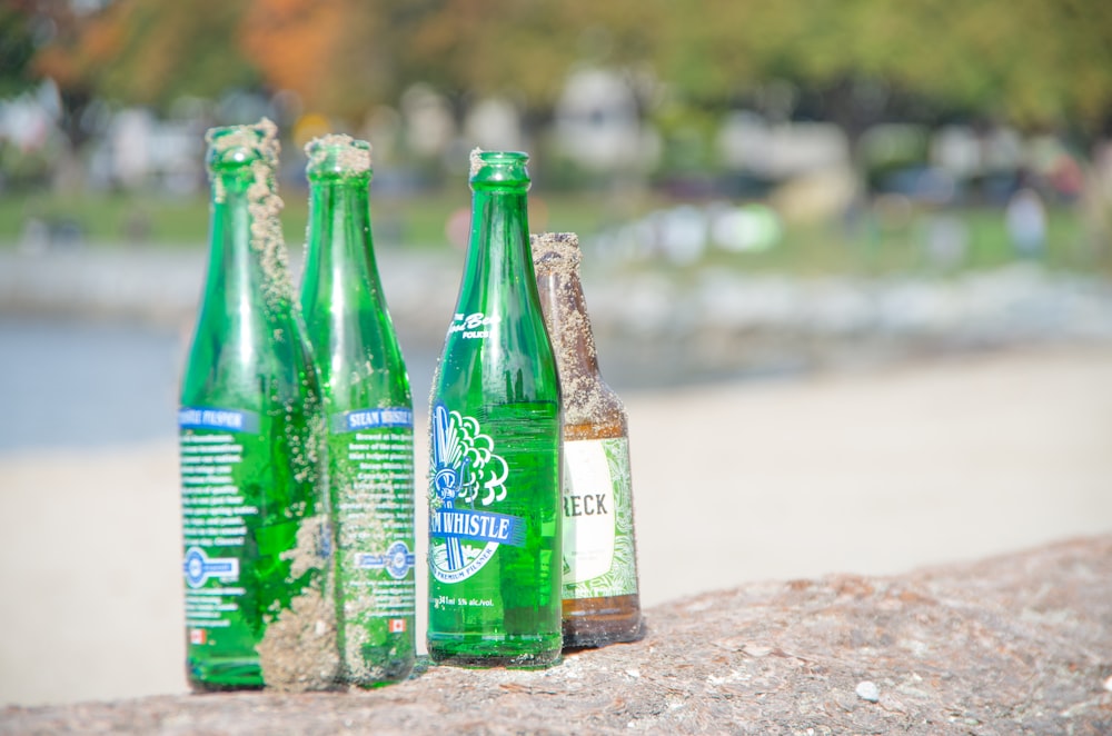 green glass bottles on brown sand
