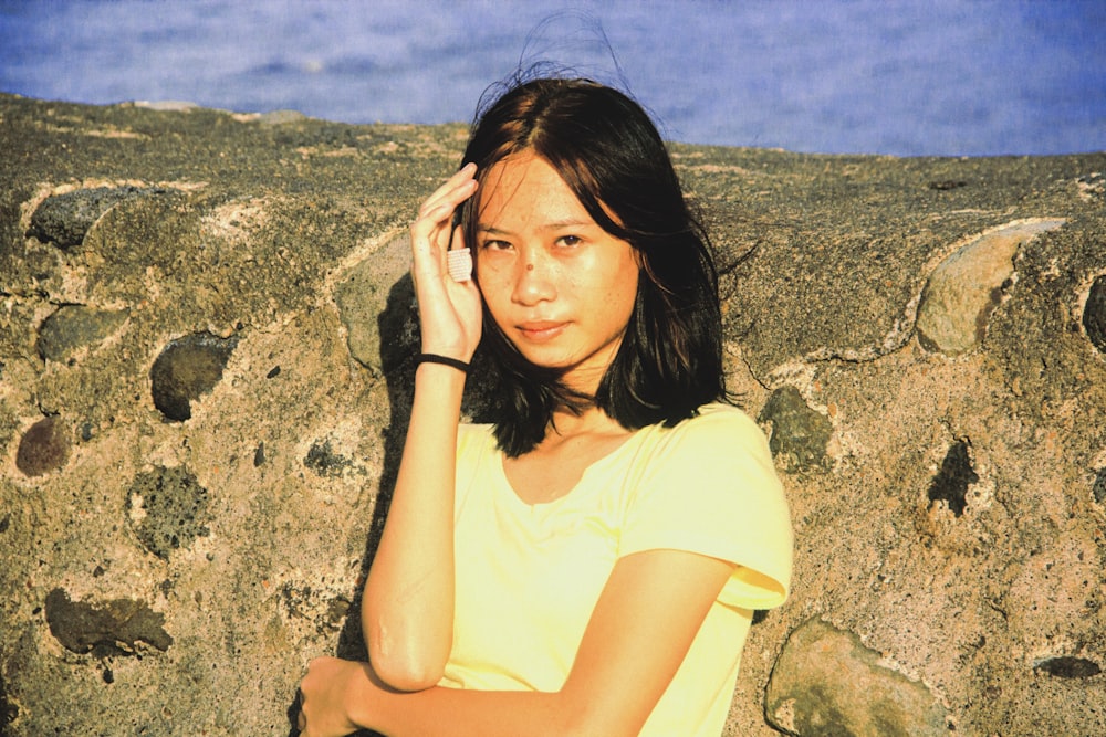 woman in yellow shirt sitting on rock