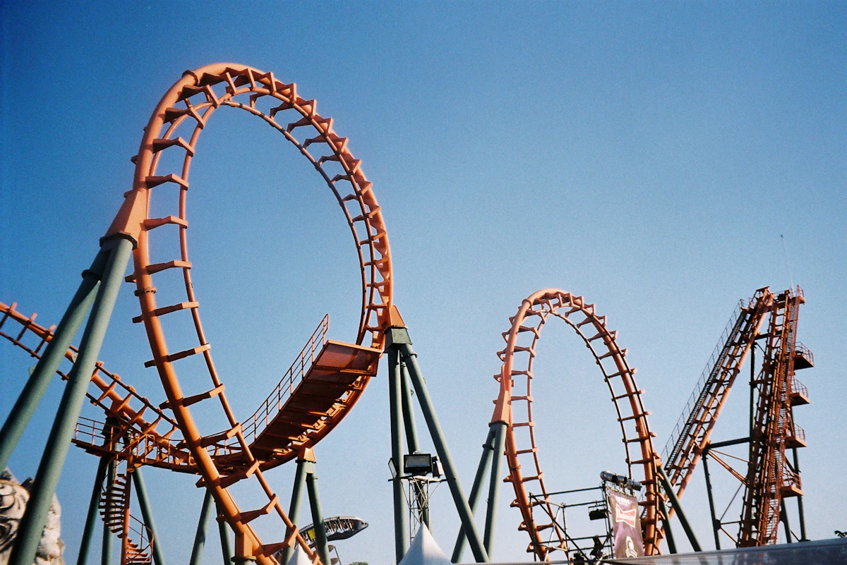 Roller coaster track curving against a bright sky at a theme park