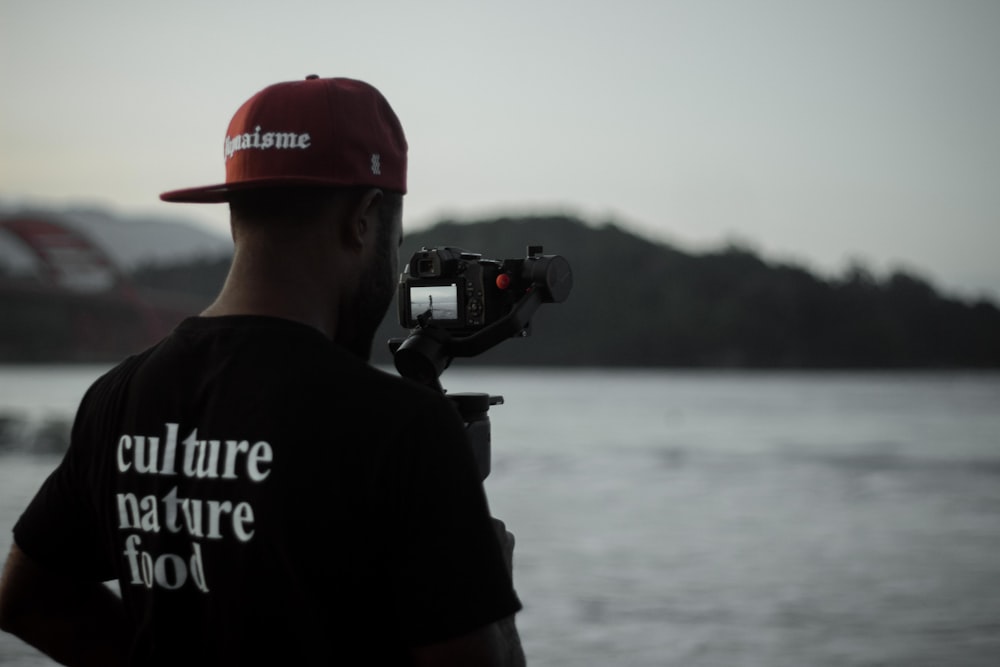 man in black and white crew neck t-shirt holding black dslr camera