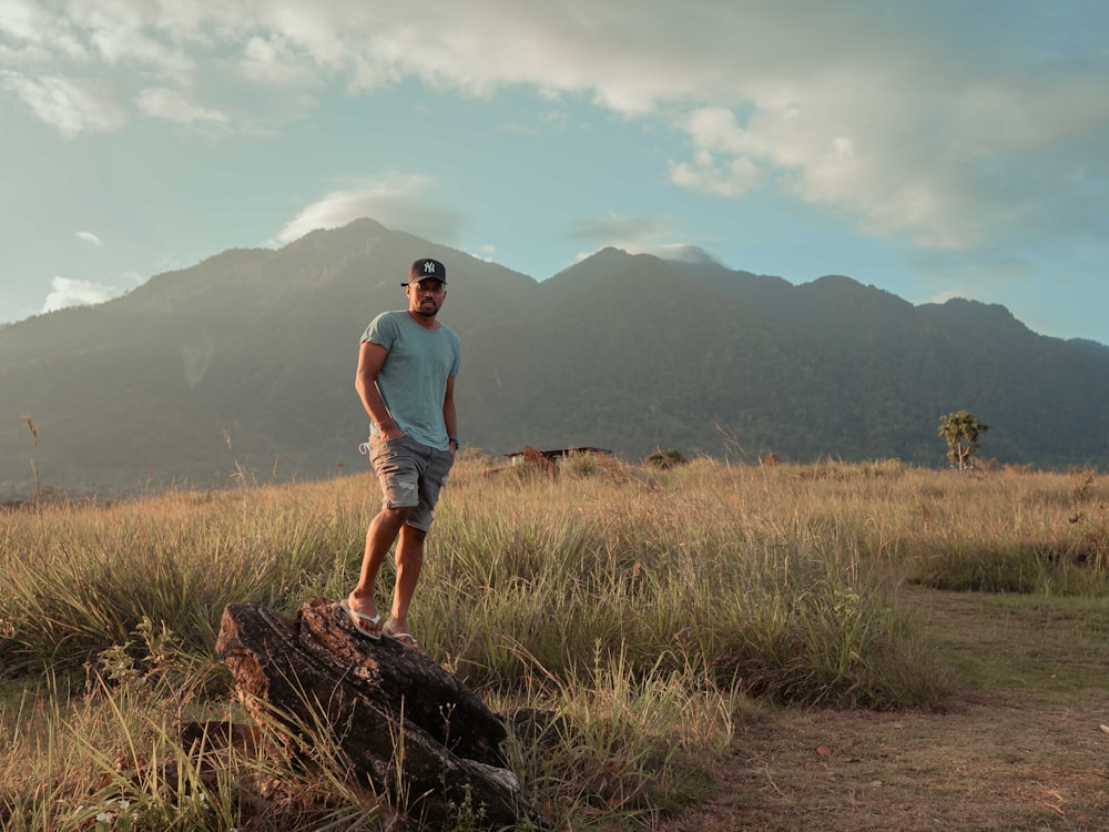 man in white t-shirt standing on brown grass field during daytime