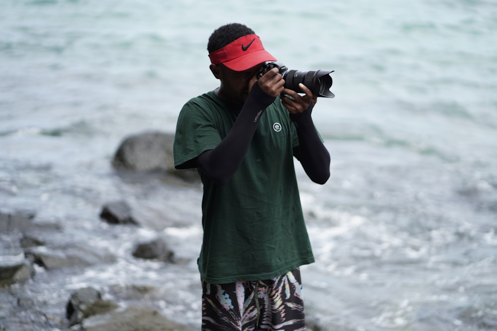 man in green shirt holding black dslr camera