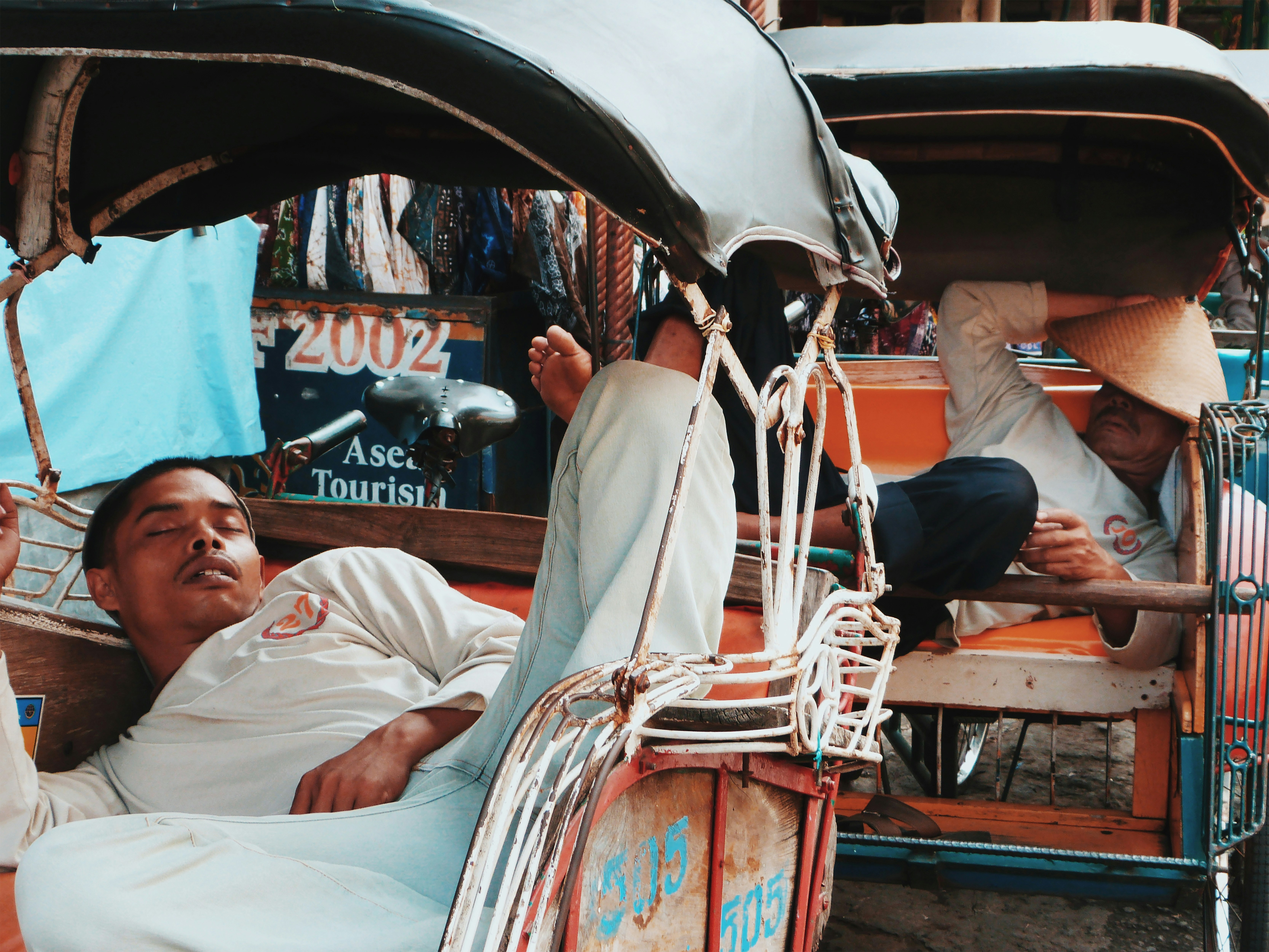 man in white thobe sitting on red and white boat during daytime