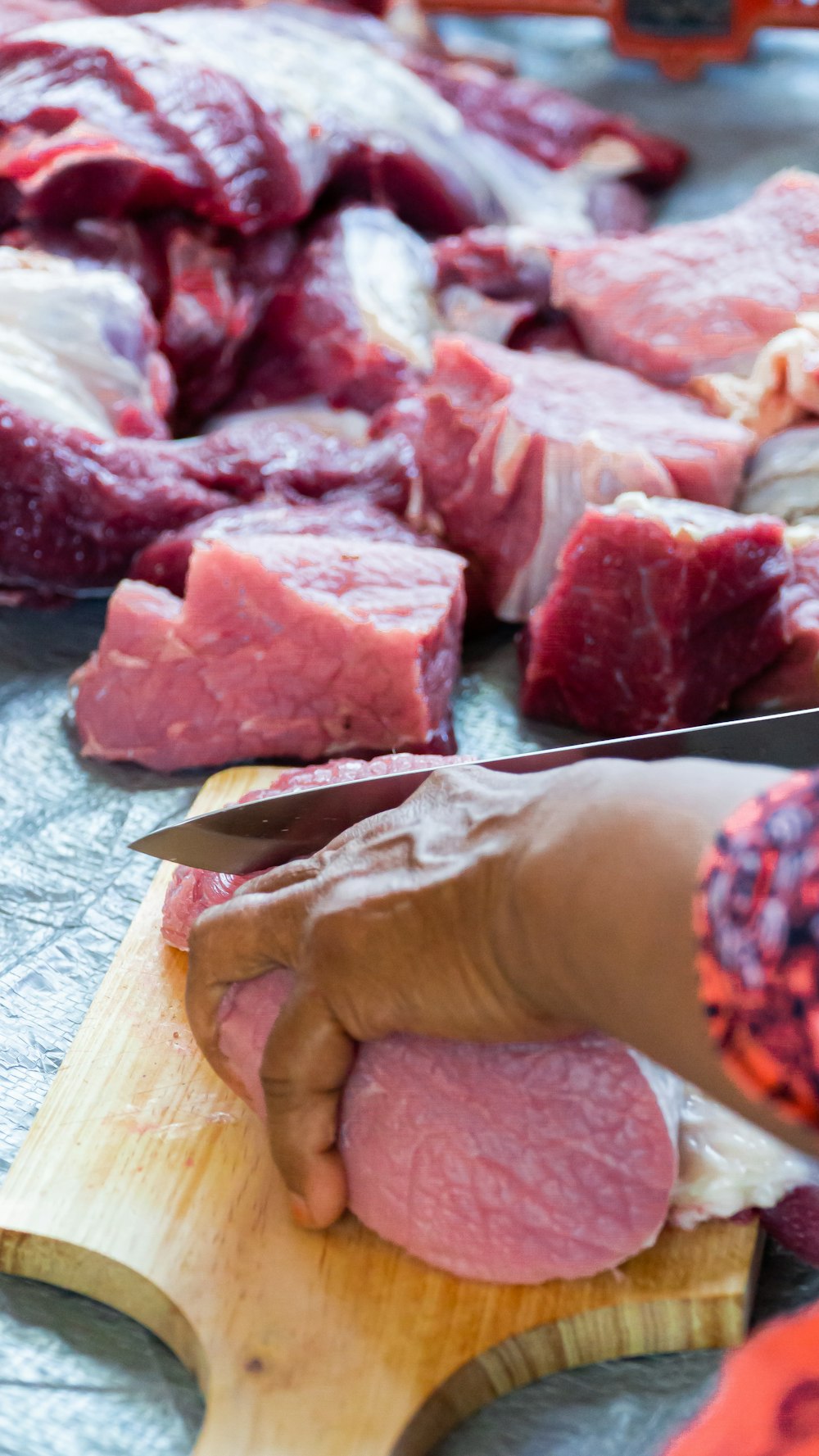 person holding raw meat on brown wooden chopping board