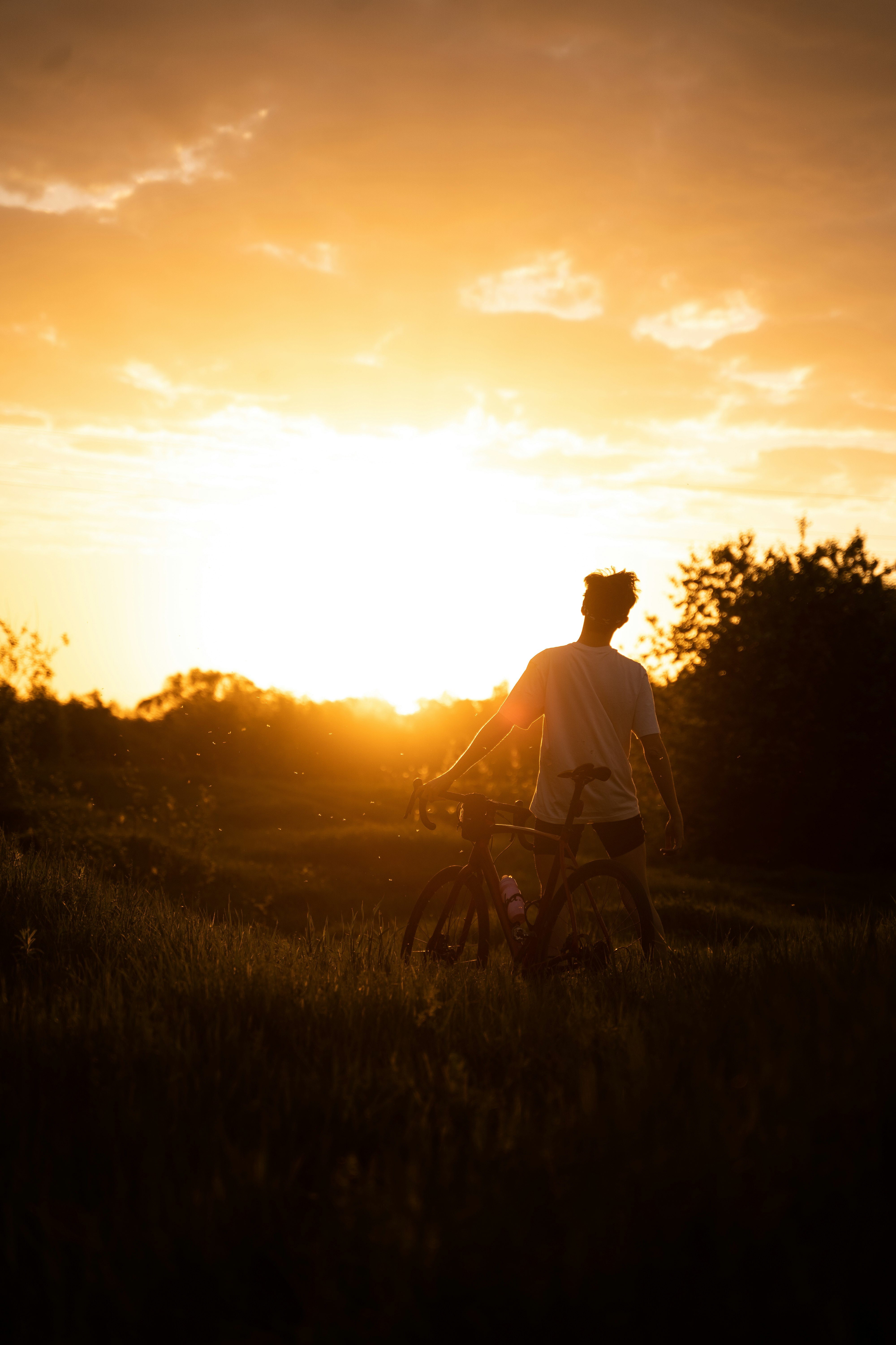 man in white shirt riding bicycle during sunset