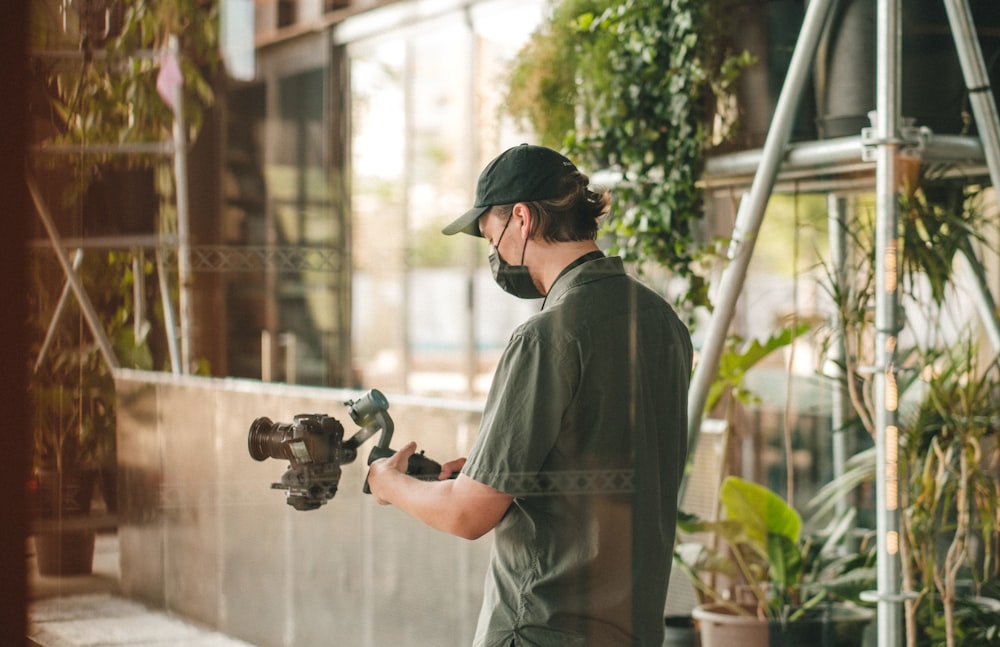 man in gray dress shirt holding black dslr camera