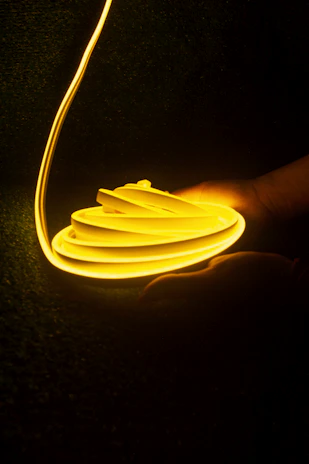 Close-up of hands crafting a glowing neon sign in a cozy workshop.
