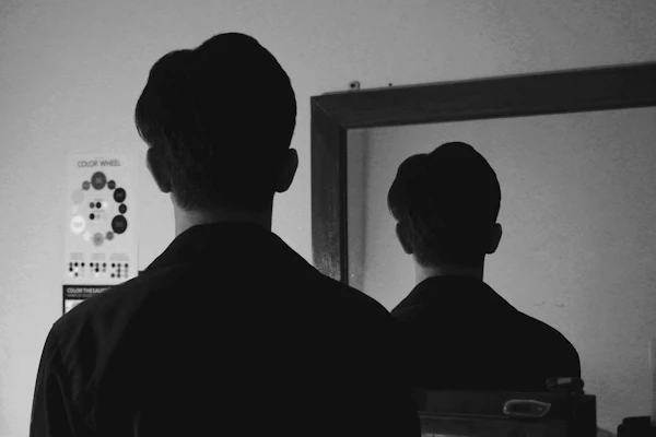 A man tying his tie in front of a mirror