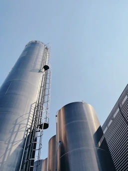 Tall metal silos with ladders against a clear blue sky