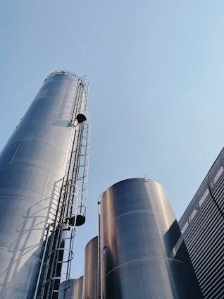 Tall metal silos with ladders against a clear blue sky