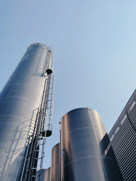 Tall metal silos with ladders against a clear blue sky