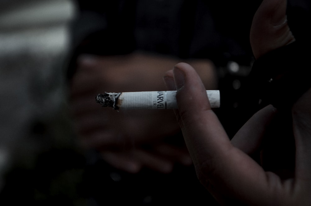 person holding white and black cigarette stick