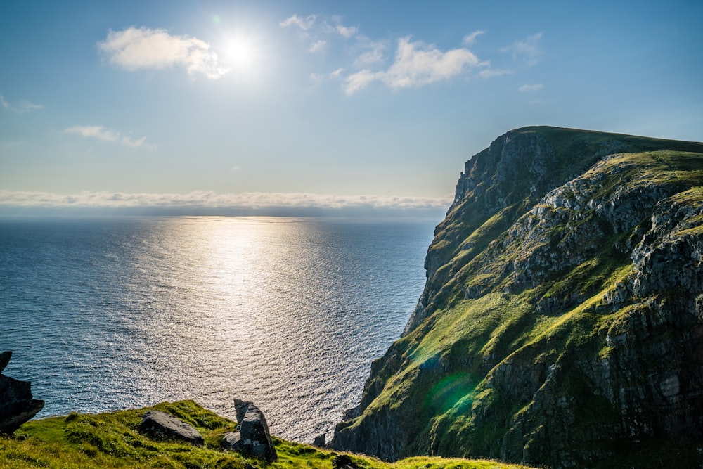 green and black mountain beside body of water during daytime