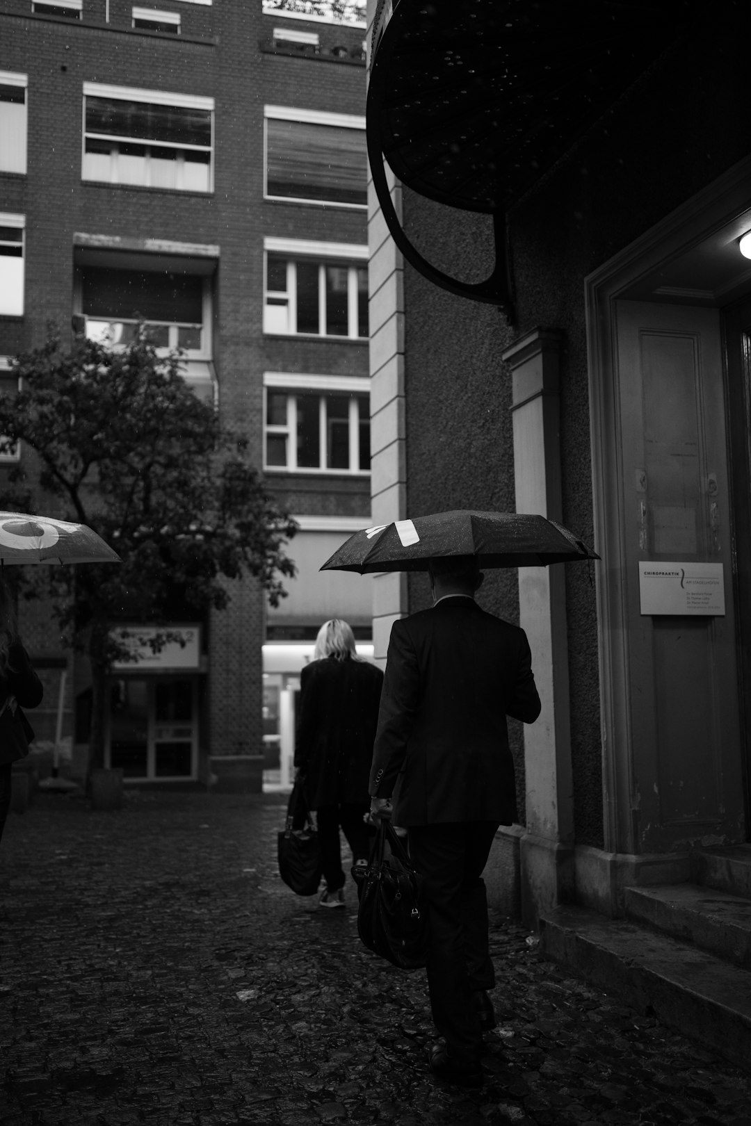 grayscale photo of man and woman walking on sidewalk