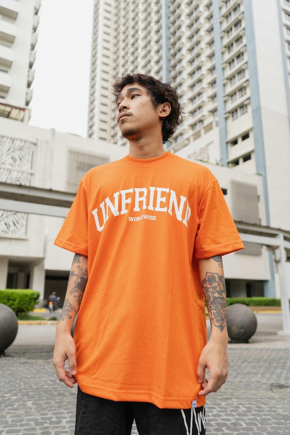 man in orange crew neck t-shirt standing near black round ball during daytime