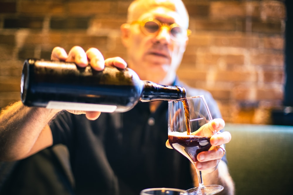 man in black crew neck shirt holding clear drinking glass