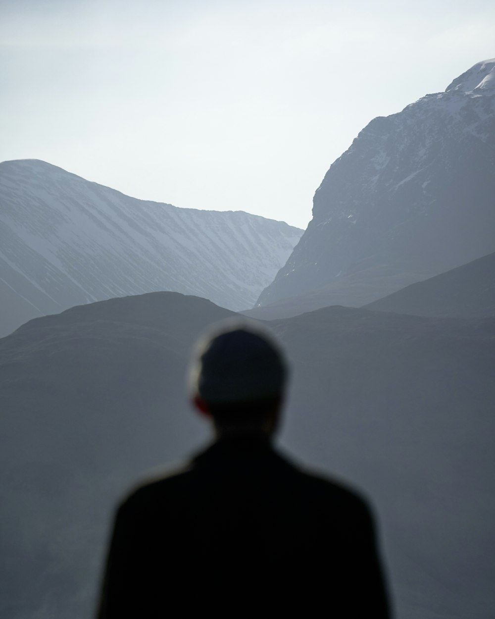hombre con chaqueta negra de pie en la cima de la montaña durante el día