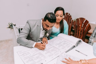 man in gray suit jacket sitting beside woman in teal long sleeve shirt