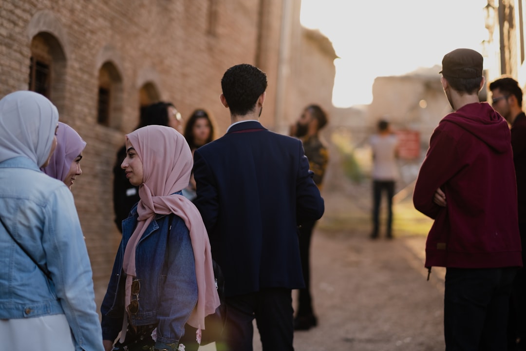 man in black coat standing beside woman in white hijab