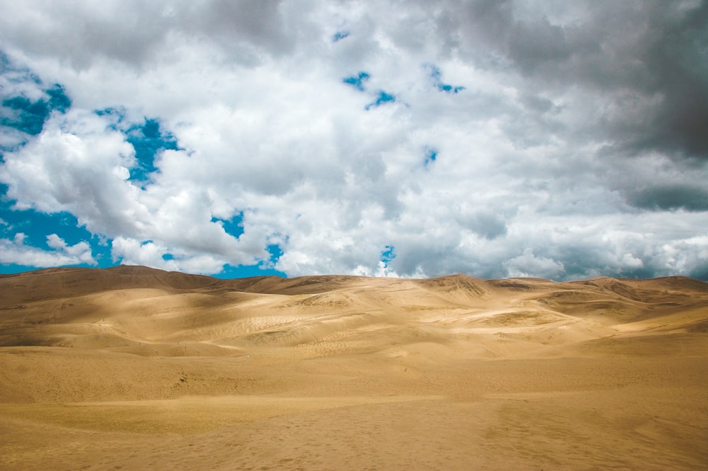 昼間、曇り空の下、砂漠を歩く人