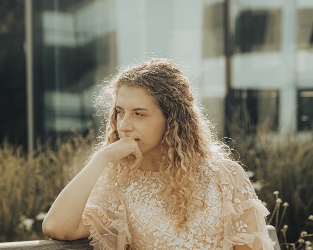 woman in white lace long sleeve shirt sitting on brown wooden bench