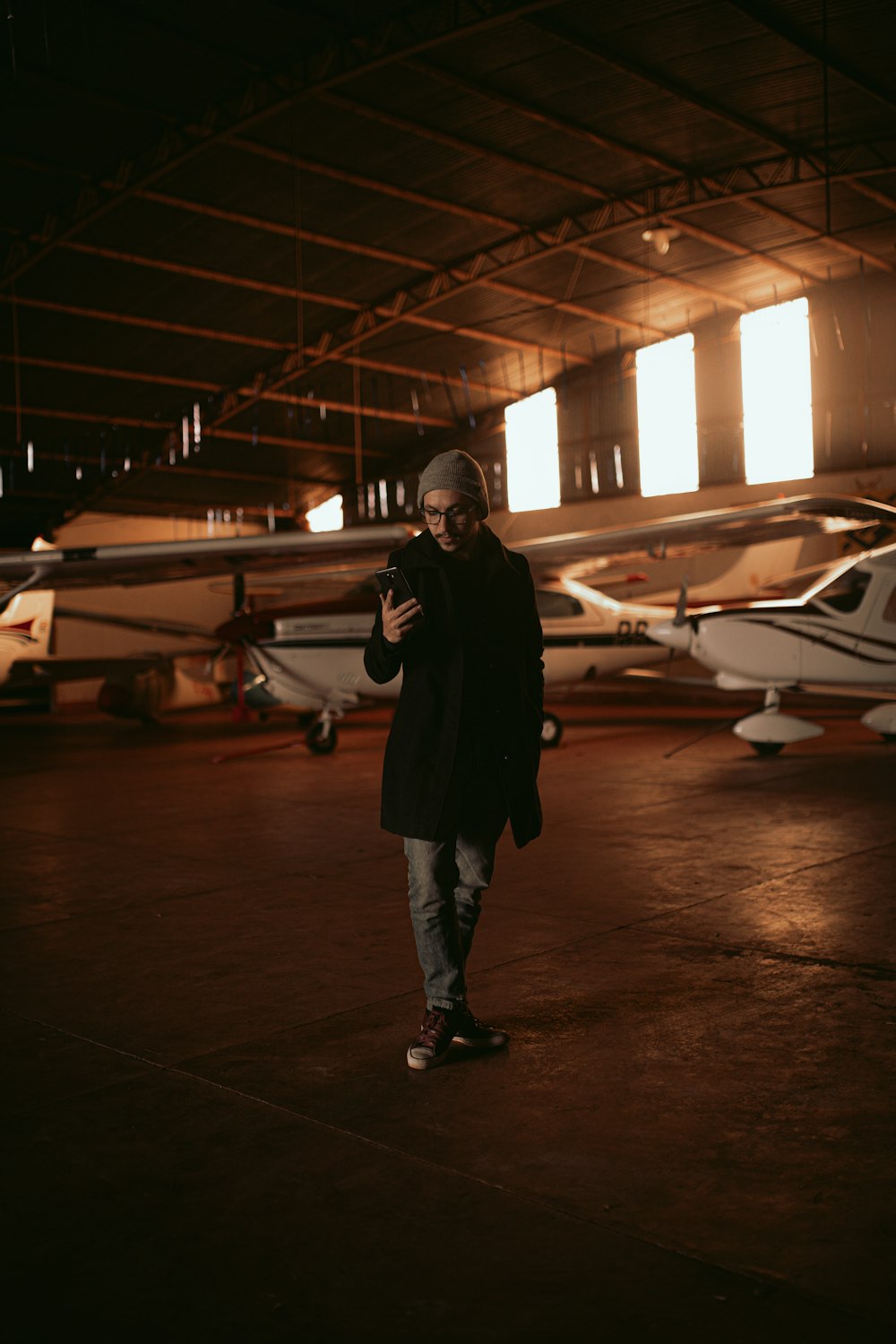 man in black jacket standing near white airplane