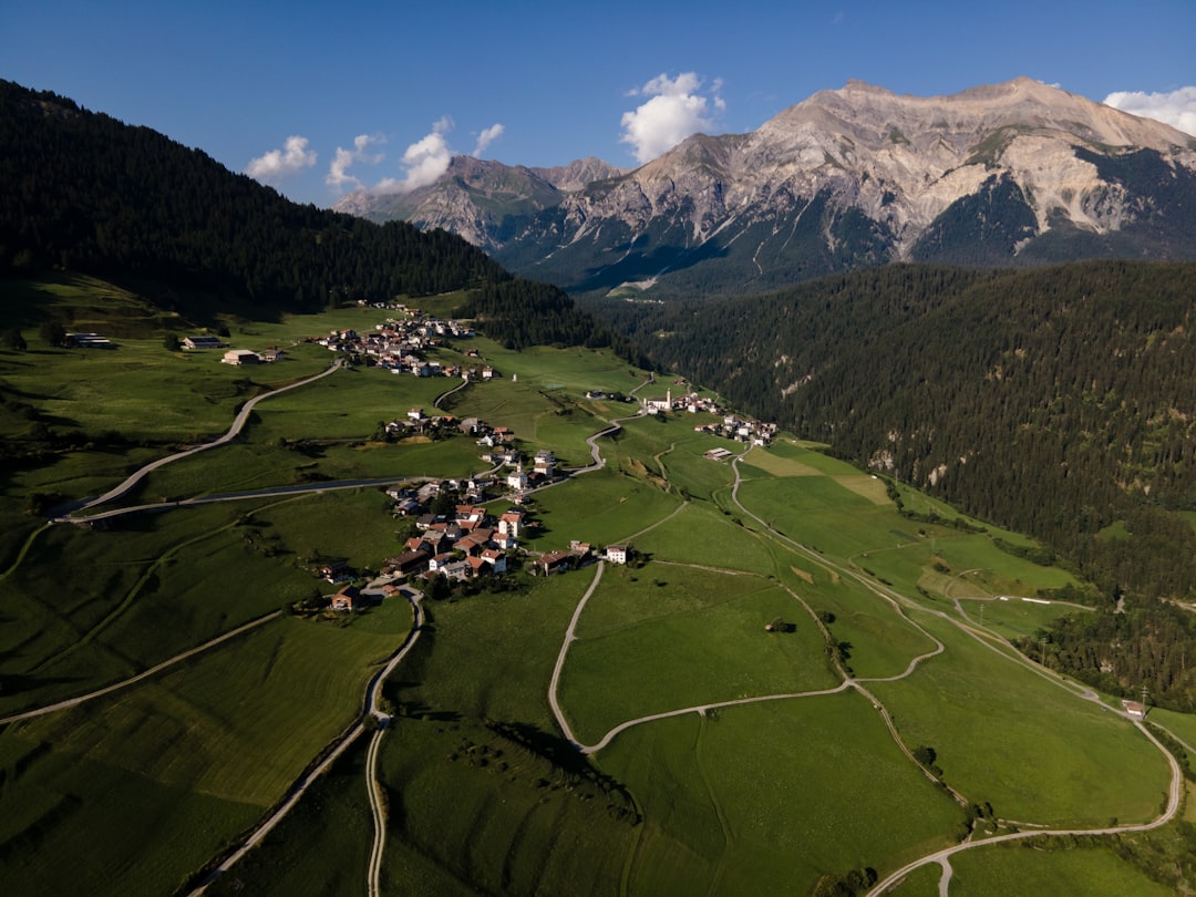 green grass field near mountain under blue sky during daytime