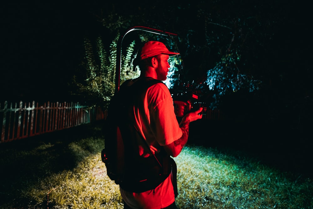 man in red jacket and black hat standing near brown wooden fence during daytime