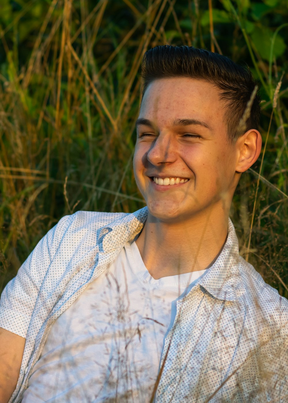 a man sitting in the grass smiling for the camera