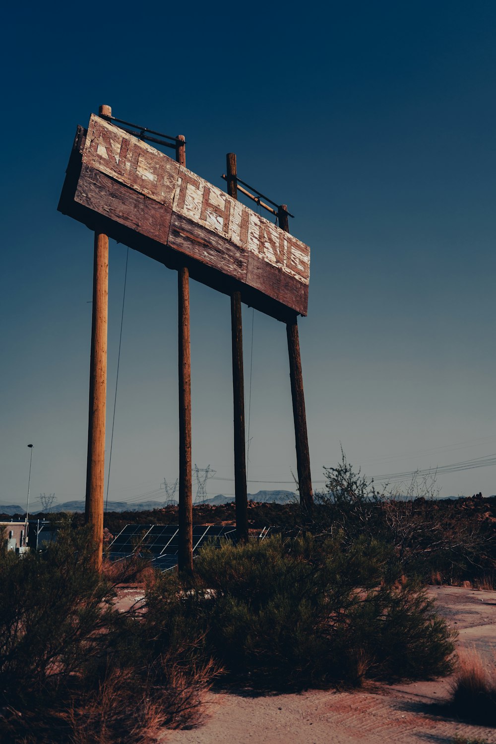 a large wooden sign sitting in the middle of a desert