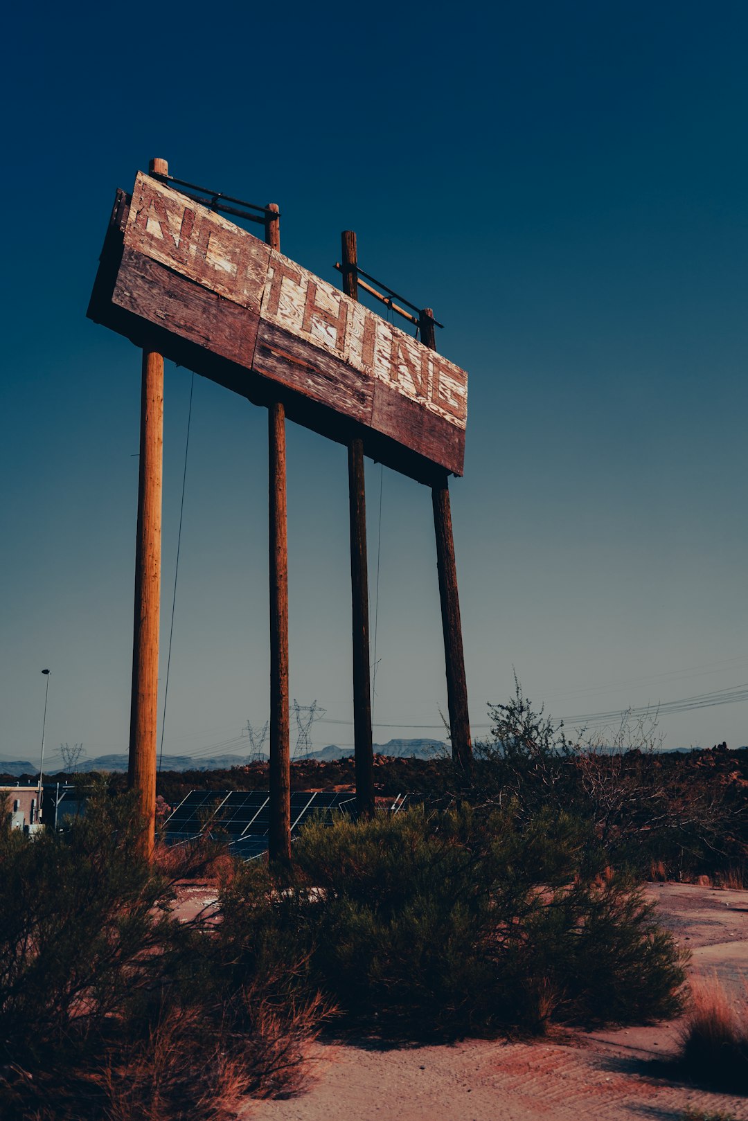 a large wooden sign sitting in the middle of a desert