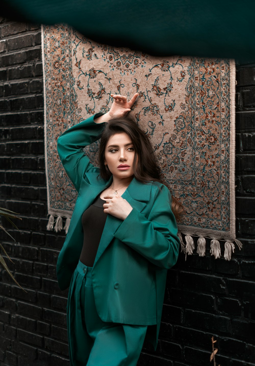 a woman in a green suit leaning against a wall