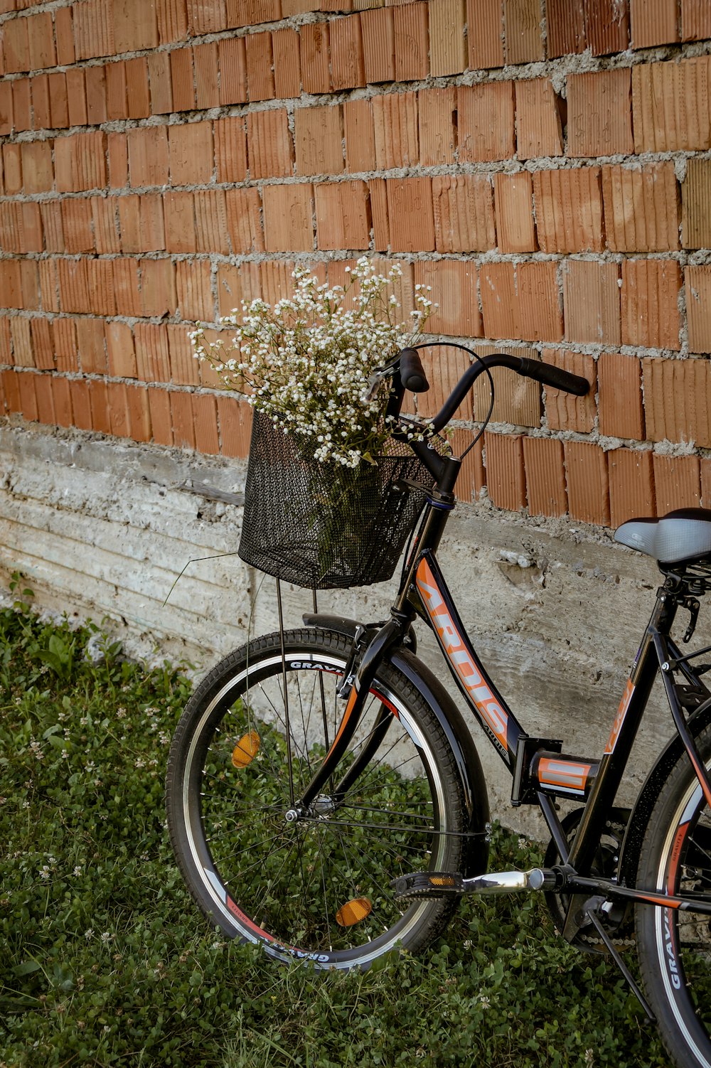 black city bike beside brown brick wall