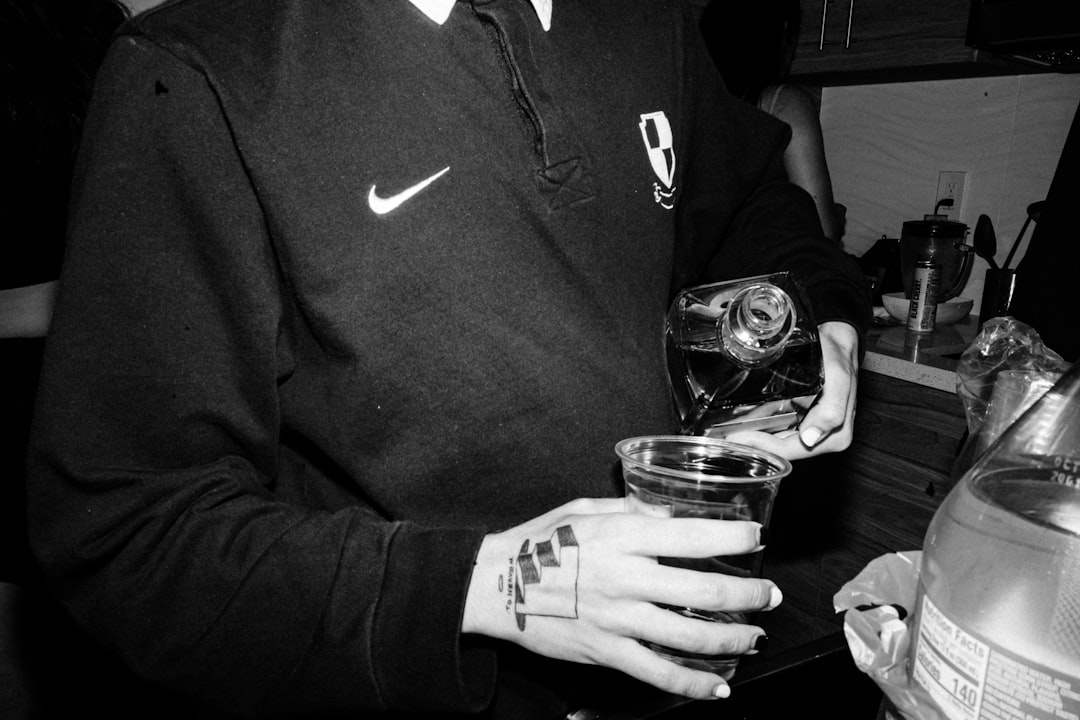 man in black and white nike hoodie holding drinking glass