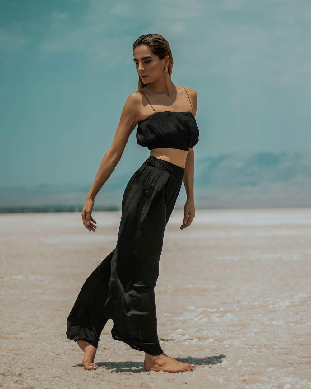 mujer en vestido de tubo negro de pie en la playa durante el día